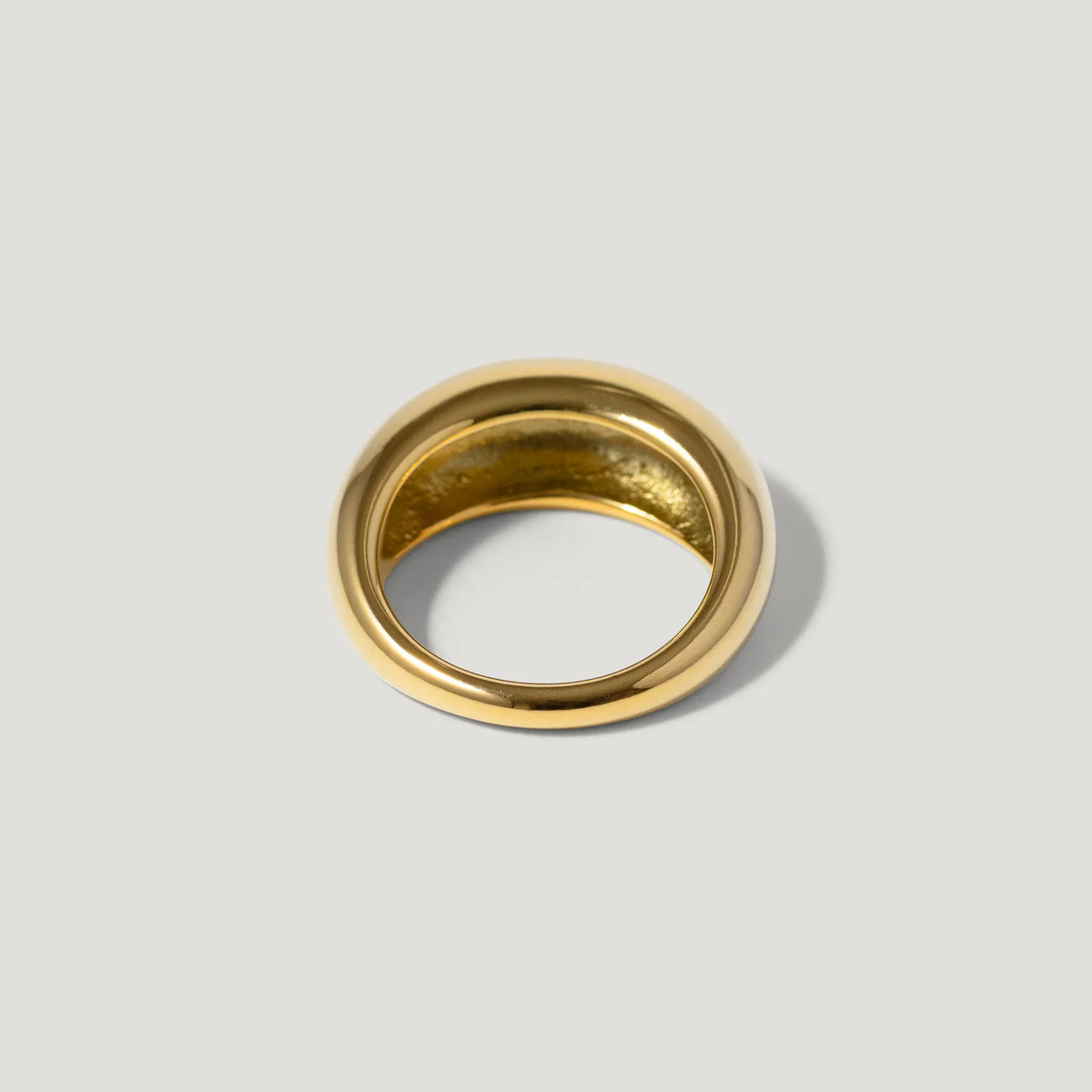 Polished gold dome ring with smooth finish on a light background