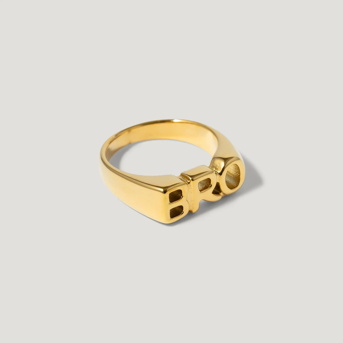 Gold ring with bold block letters spelling BRO on a neutral background