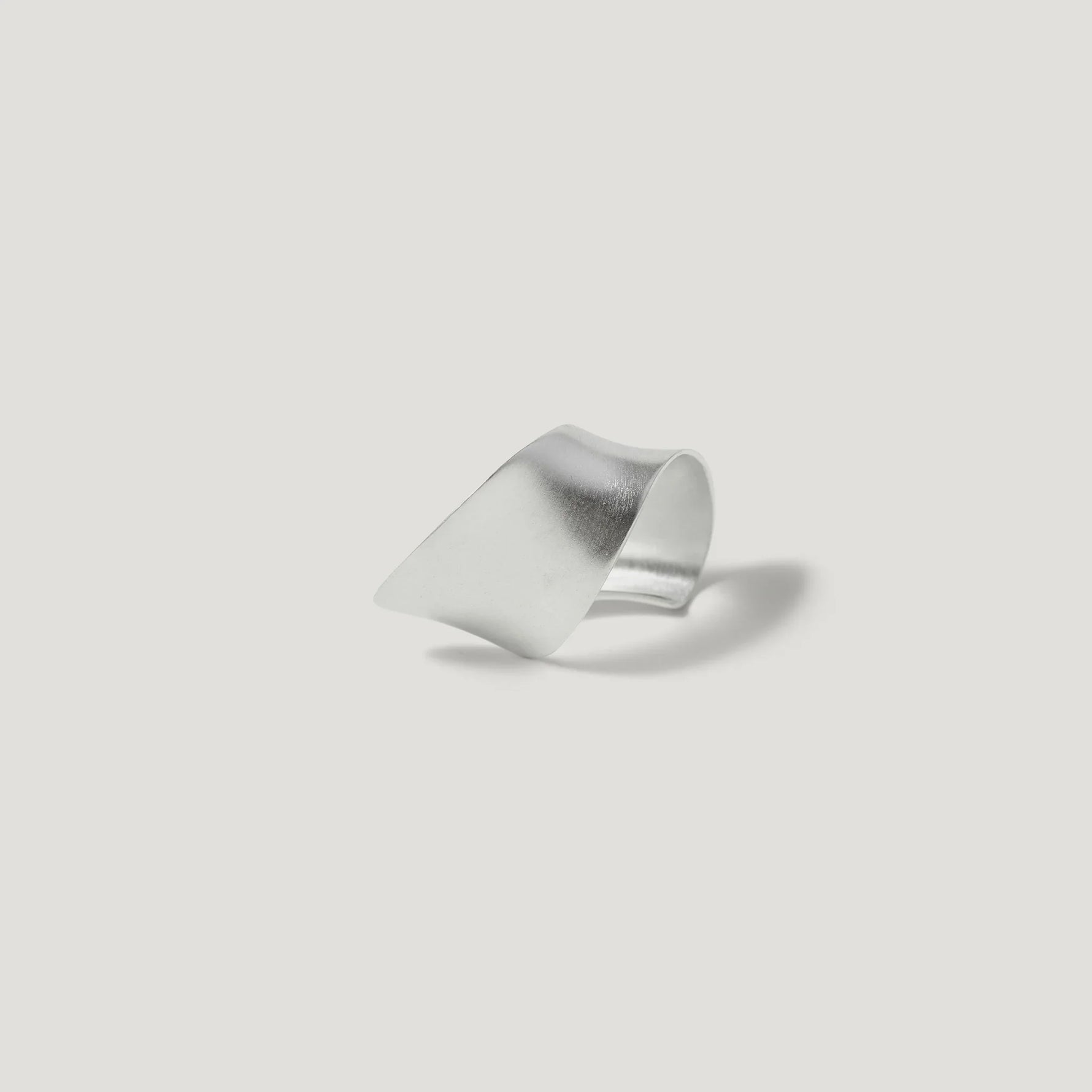 Modern silver sculptural ring with a matte finish on white background