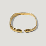 Elegant gold cuff bracelet with smooth, minimalist design on a light background