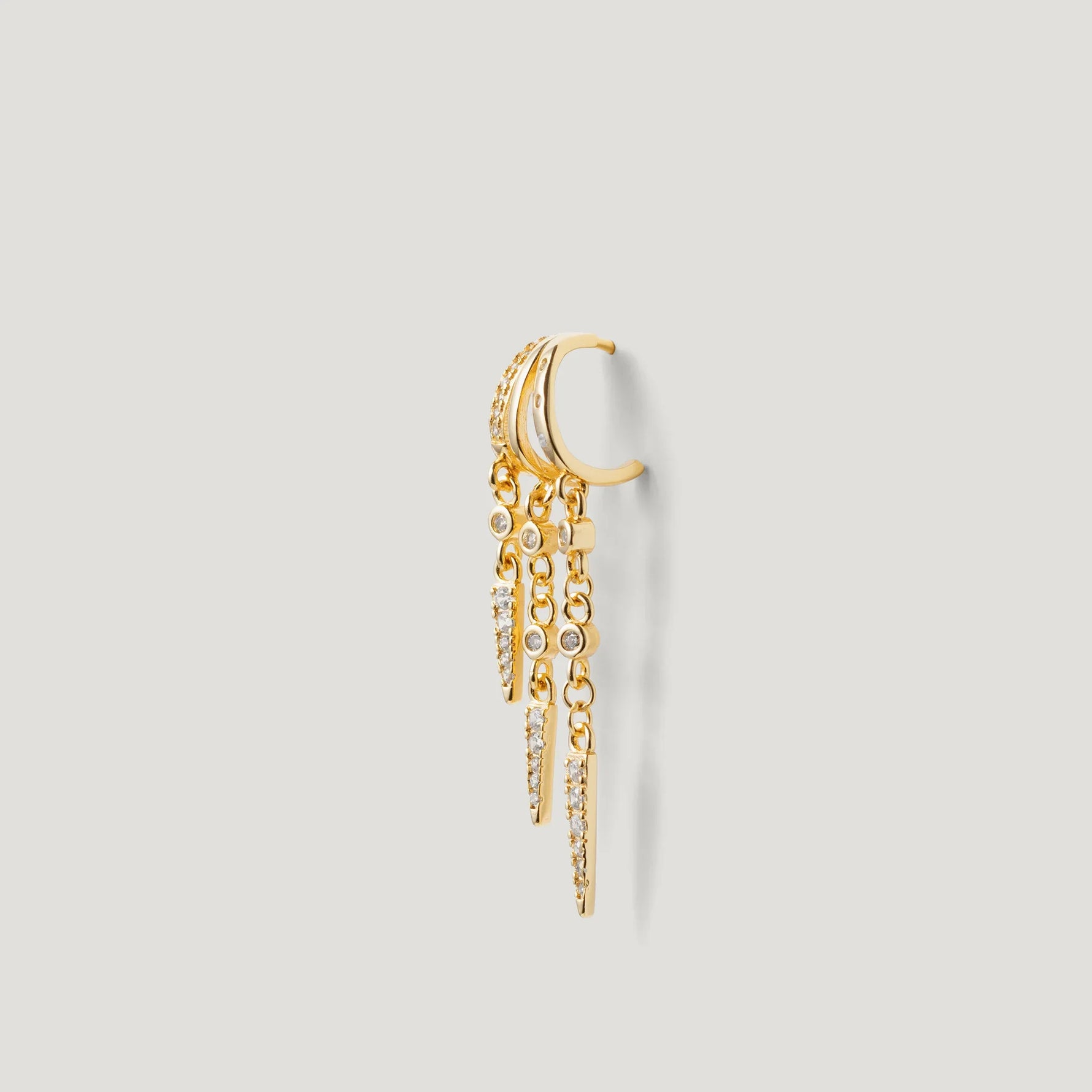 Gold hoop earring with dangling chain and sparkling crystal accents on a light background