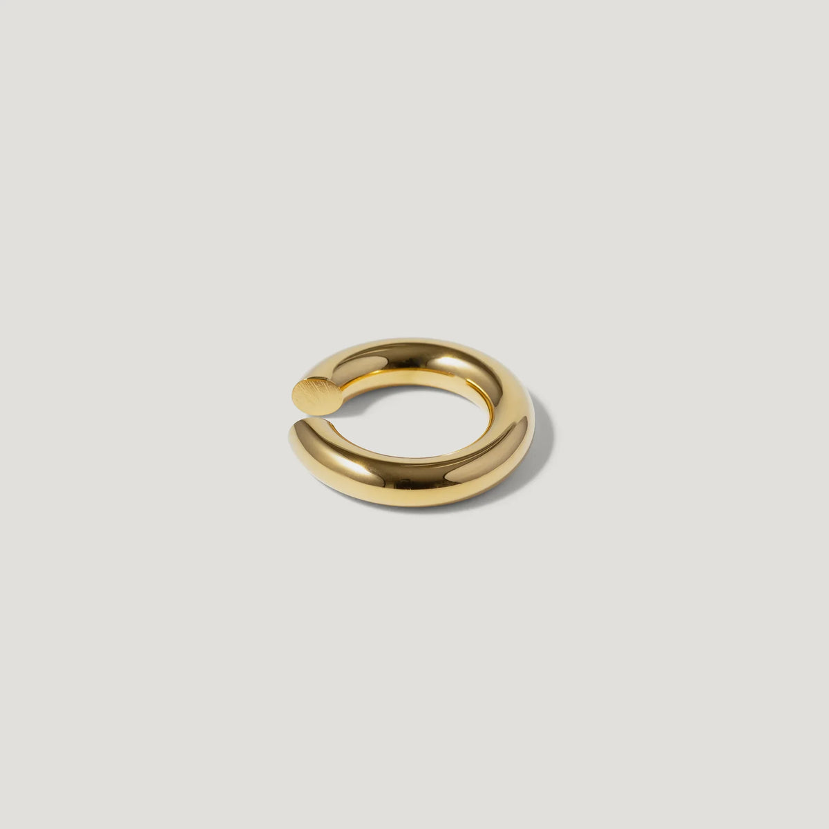 Minimalist gold open ring with smooth, polished finish on a light background