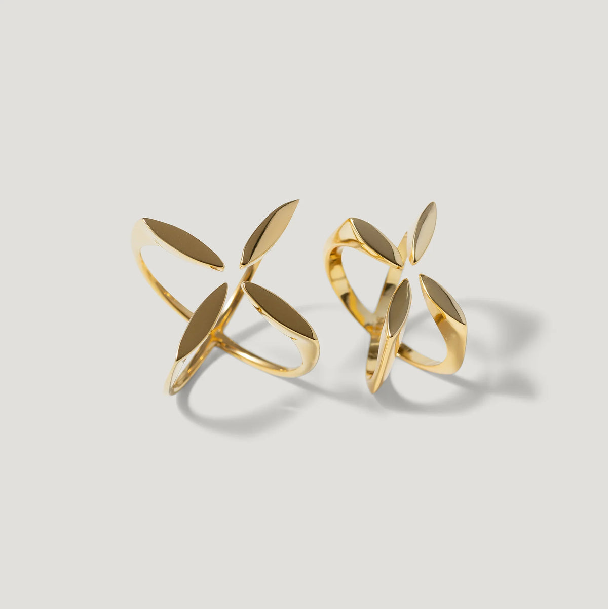 Pair of gold openwork statement rings with leaf-inspired modern design on white background