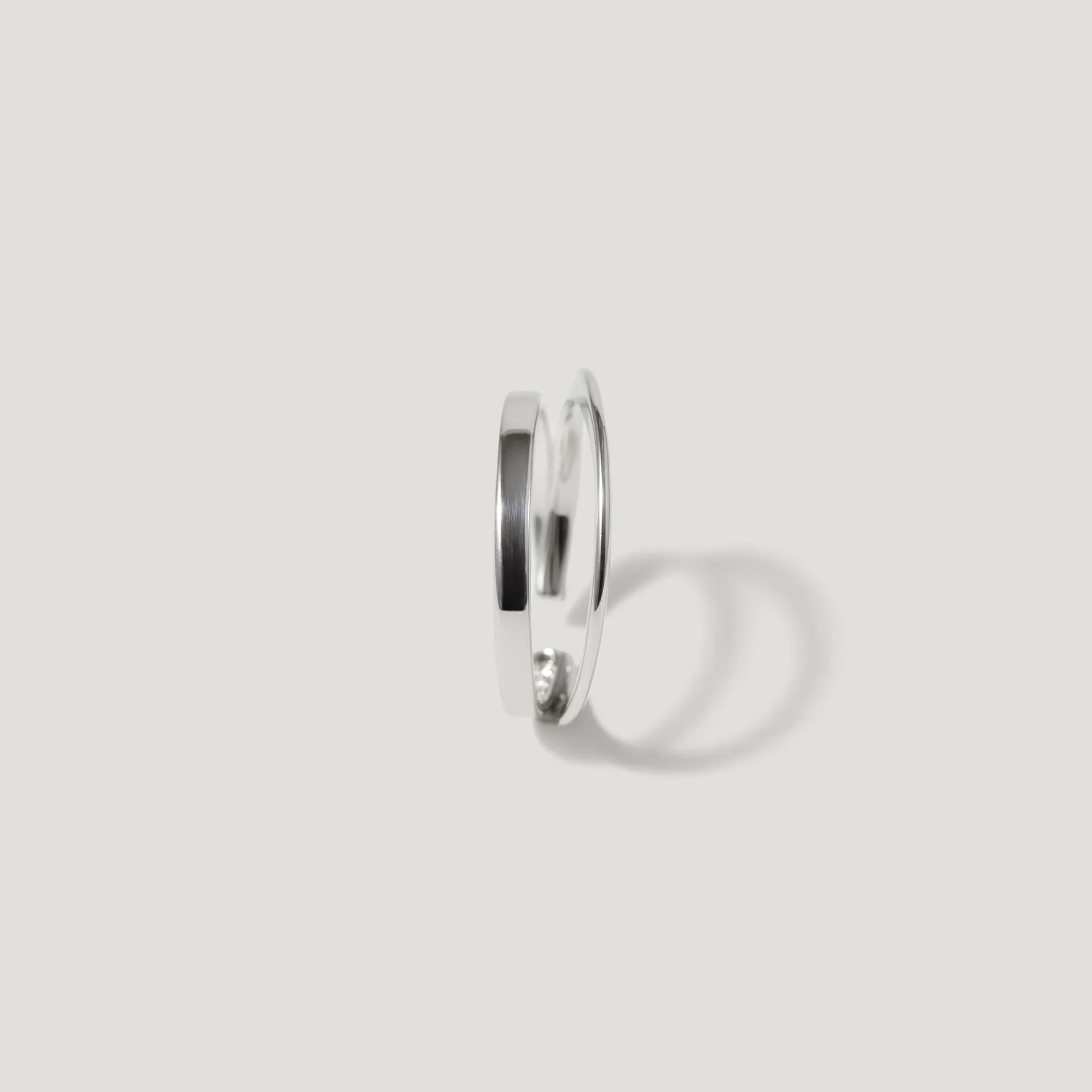 Minimalist silver open ring with a smooth, polished finish on a white background