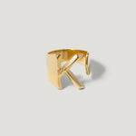 Gold open band ring with a bold letter K initial design on a light background