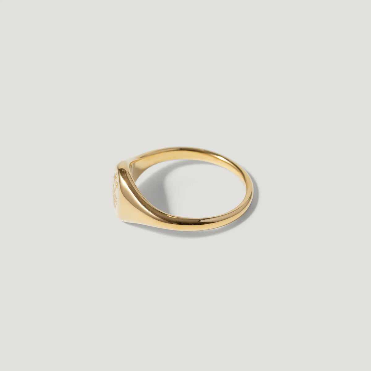 Minimalist gold signet ring on light background, fine jewelry, elegant design