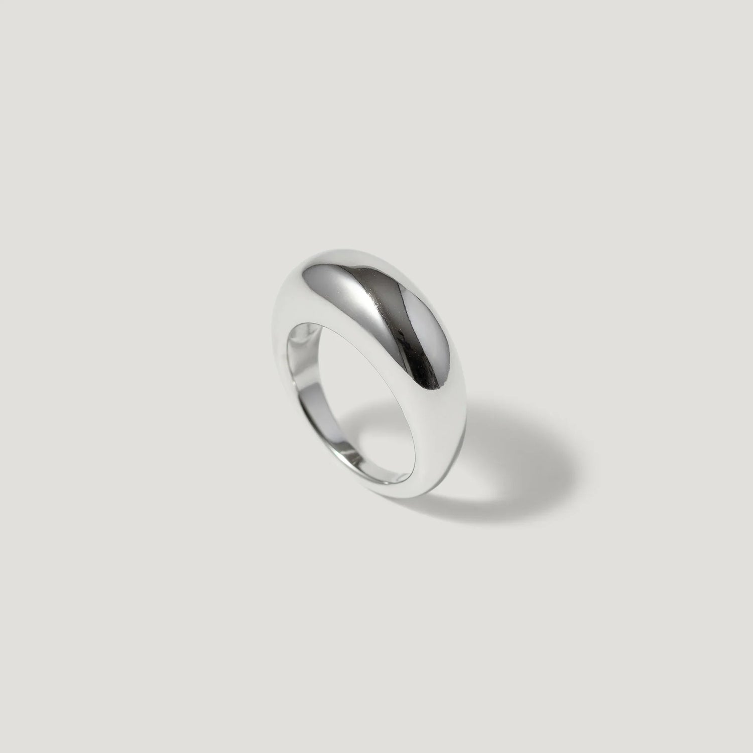 Minimalist chunky silver dome ring on a light grey background