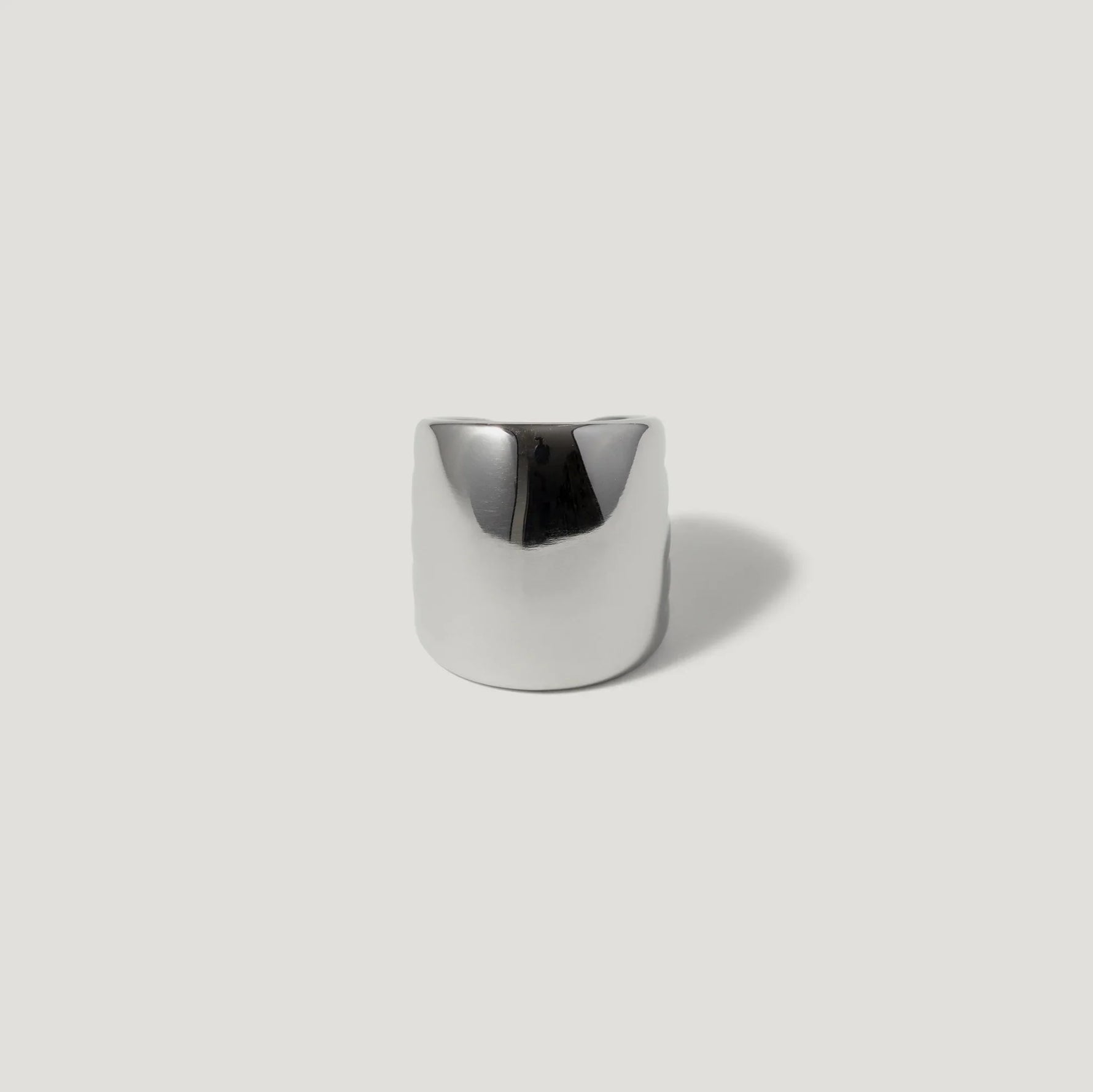 Wide silver statement ring with smooth, polished finish on a light background