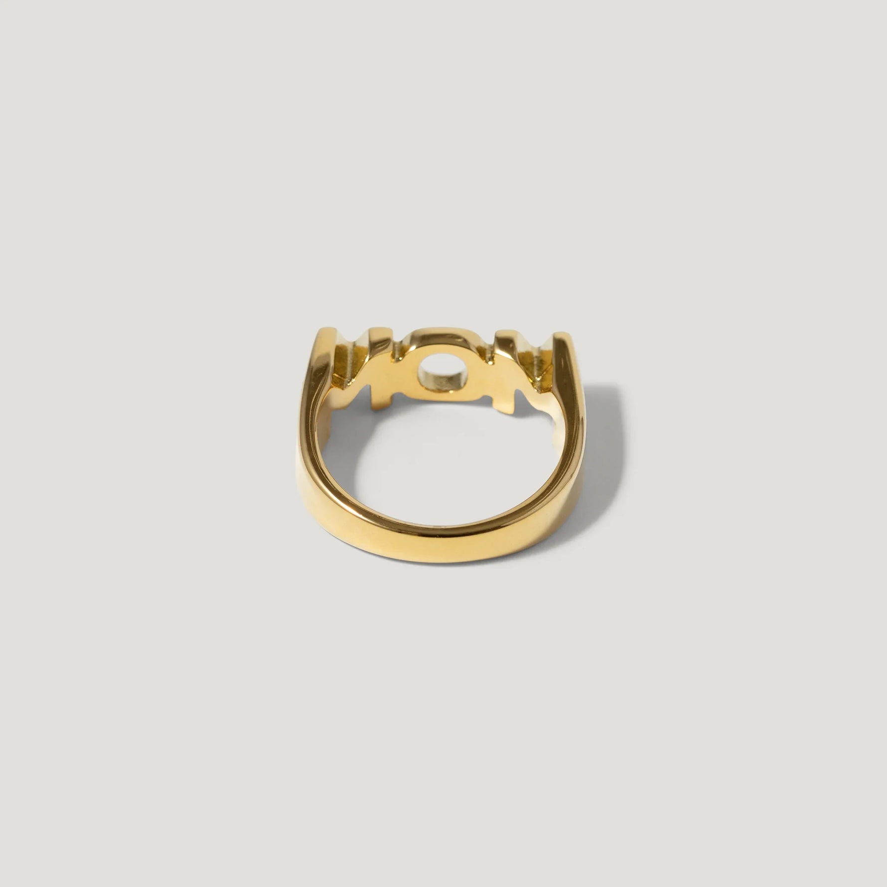 modern gold ring with geometric openwork design on neutral background