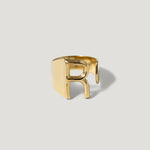 Gold adjustable ring featuring a bold cut-out letter R design on a plain background.
