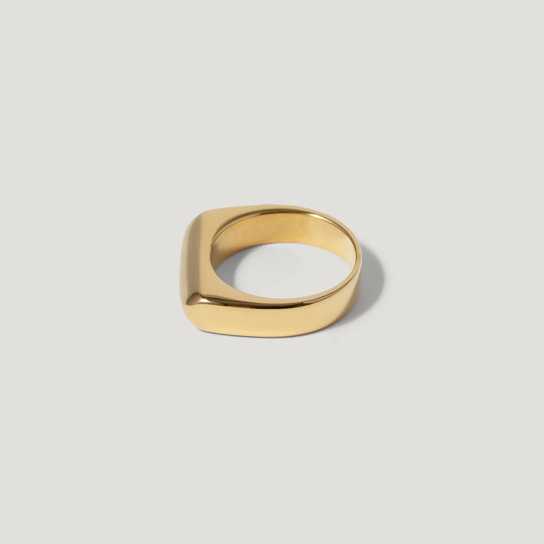Minimalist gold square ring with smooth finish on a light background