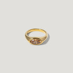 Gold ring with marquise-cut peach gemstone on neutral background