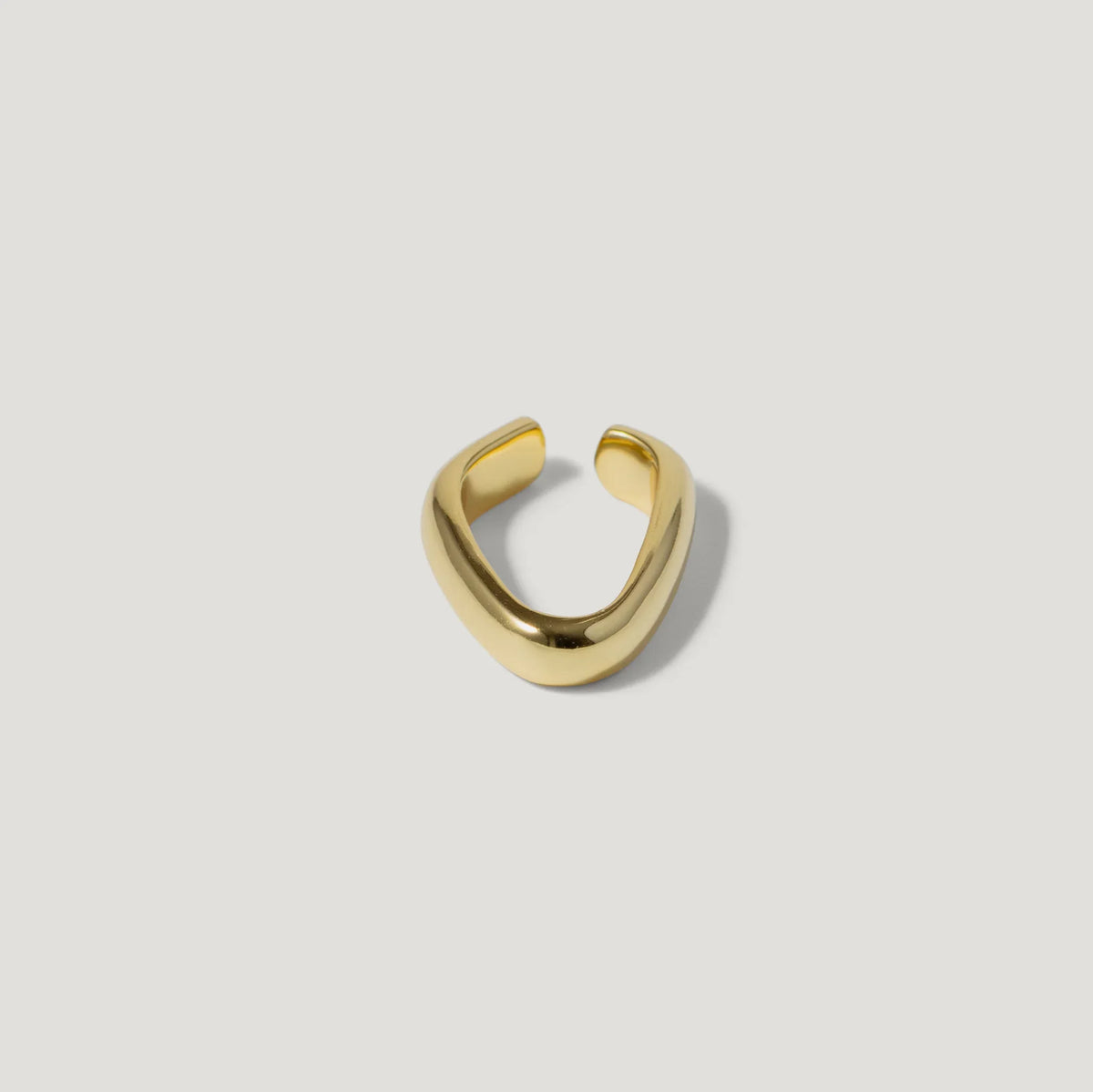 Minimalist gold open ring with a smooth, curved band on a white background