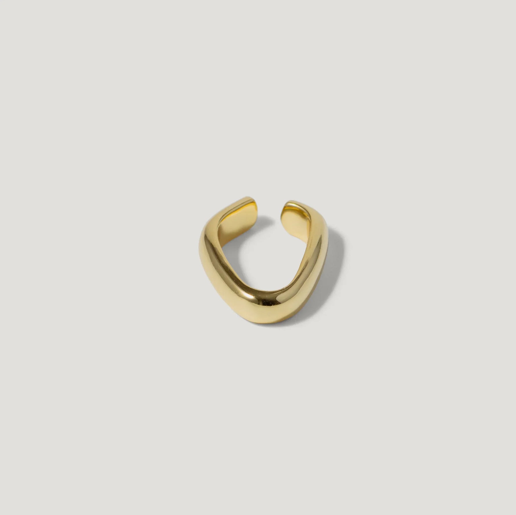 Minimalist gold open ring with a smooth, curved band on a white background