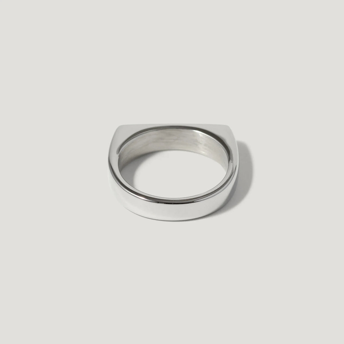 Minimalist silver signet ring with flat top on white background