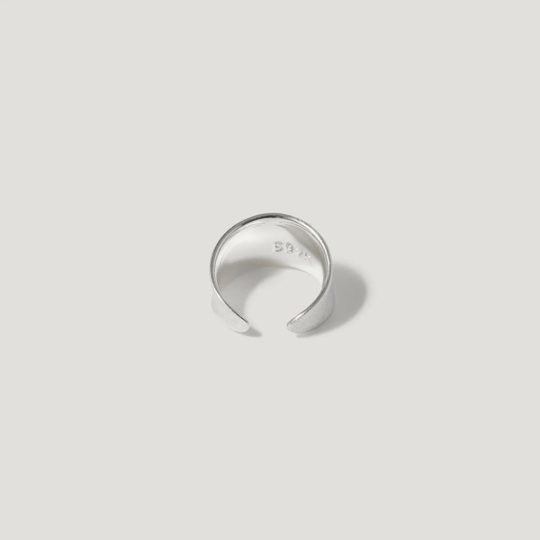 Minimalist open silver ring with smooth finish on a light neutral background