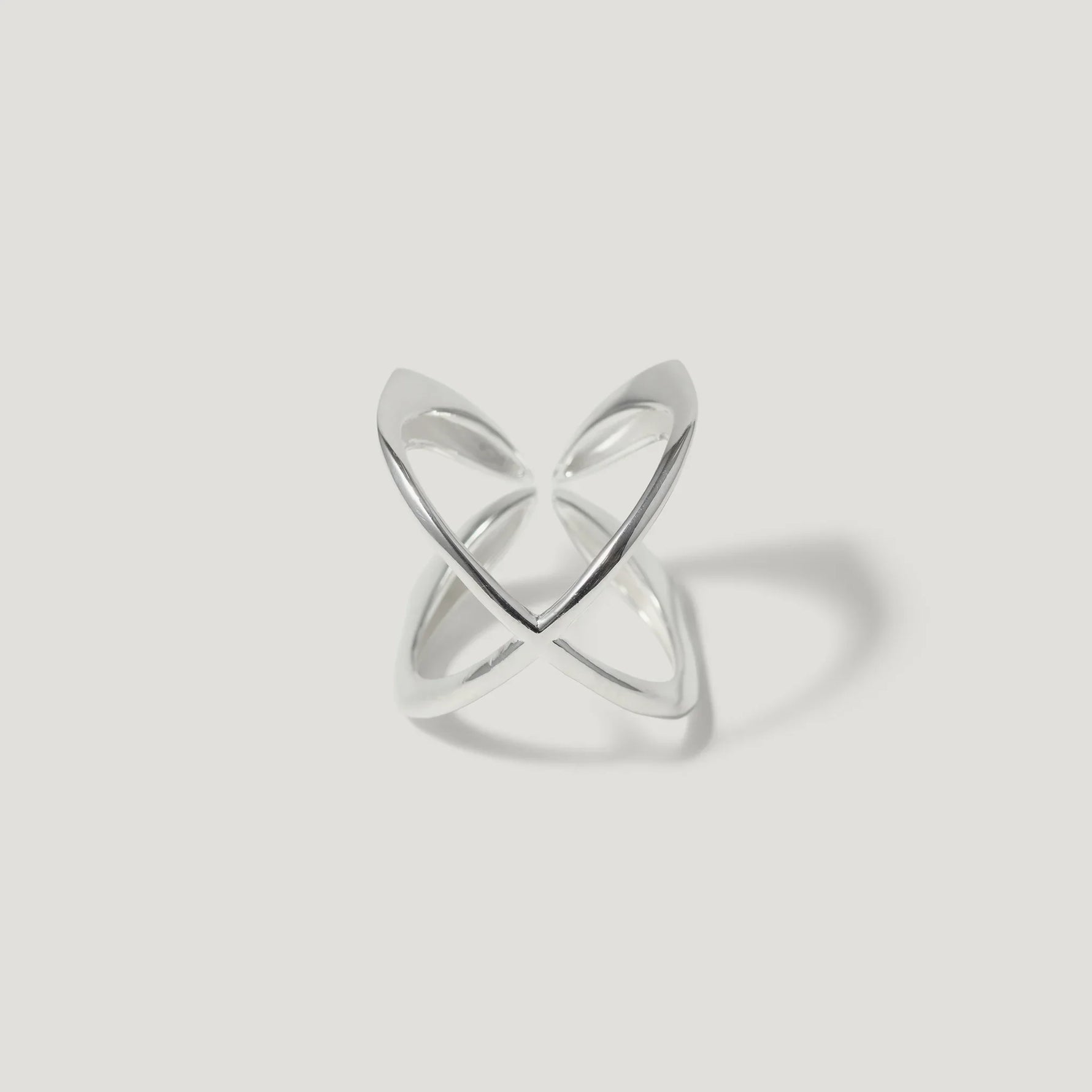 Minimalist open silver ring with intersecting bands on white background