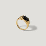 Gold ring with a faceted black gemstone on a light background