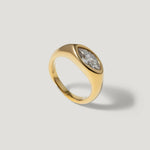 Gold ring with marquise-cut clear gemstone on matte background, modern jewelry design