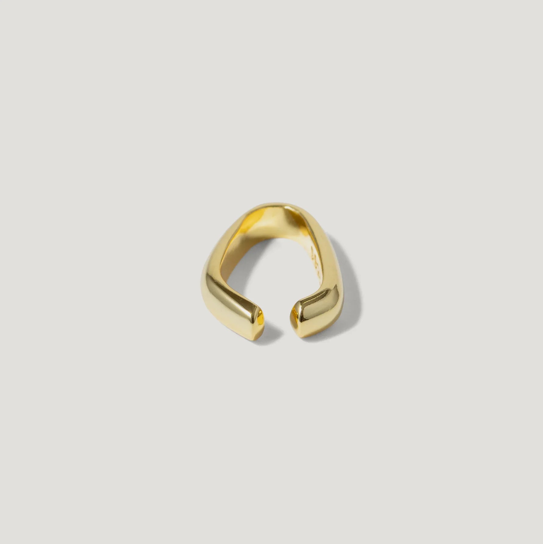 Minimalist open gold ring with smooth, polished finish on white background