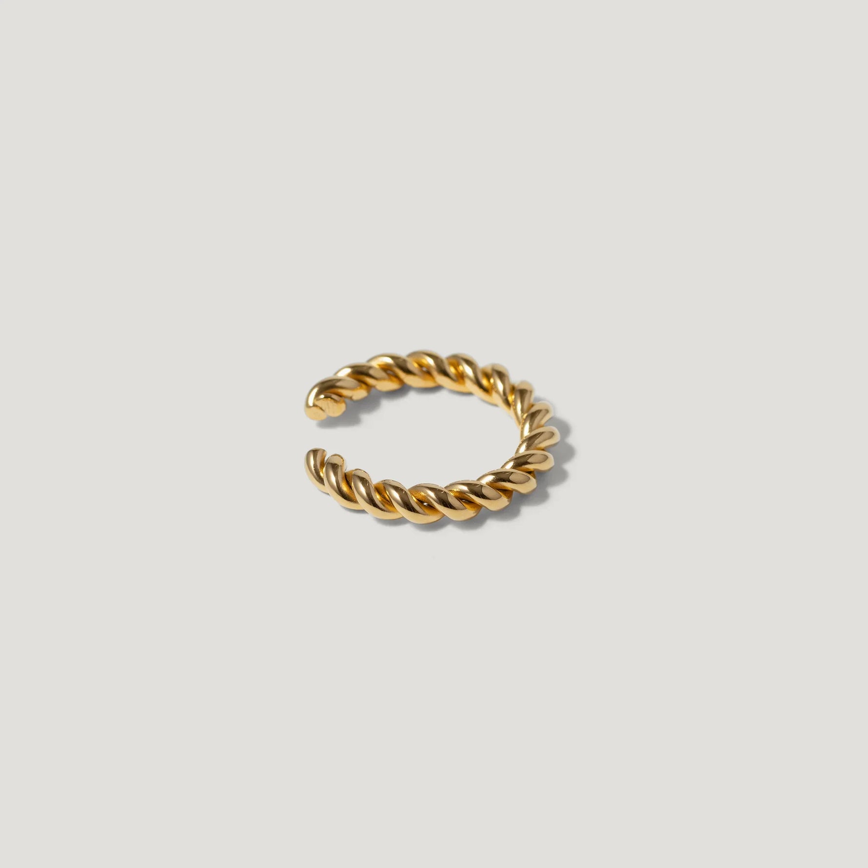 Gold twisted rope ring with open band on white background