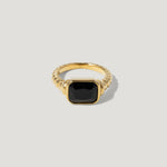 Gold ring with a square black gemstone and textured band on a light background