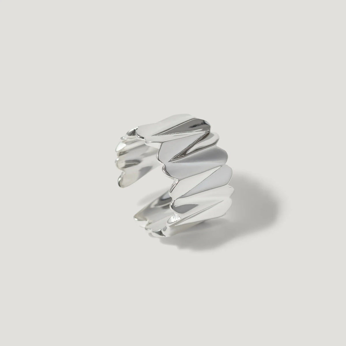 Modern silver ring with sculpted, folded design on a plain white background