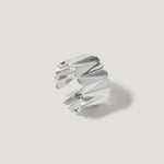 Modern silver ring with sculpted, folded design on a plain white background