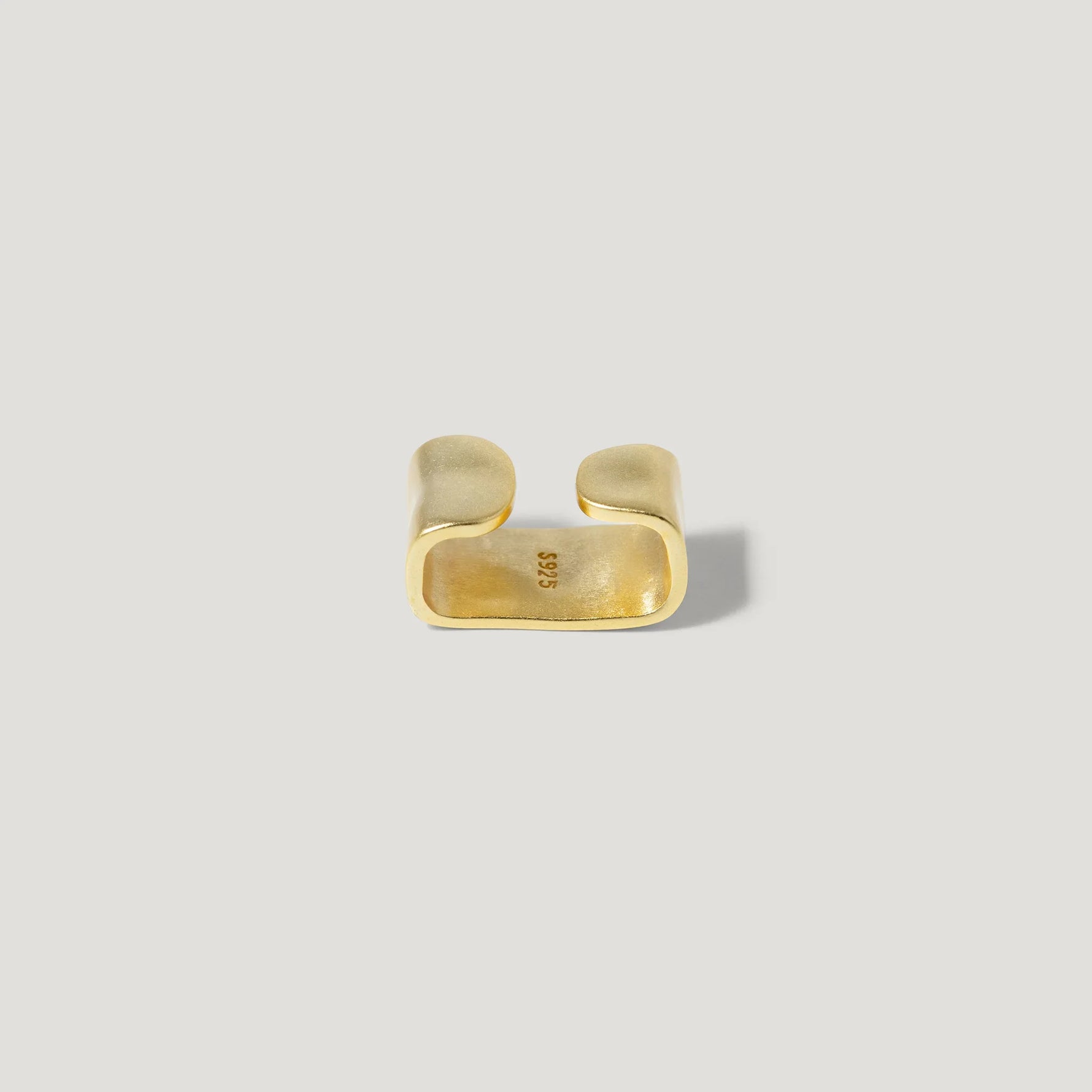 Minimalist gold open ring with smooth finish on light background