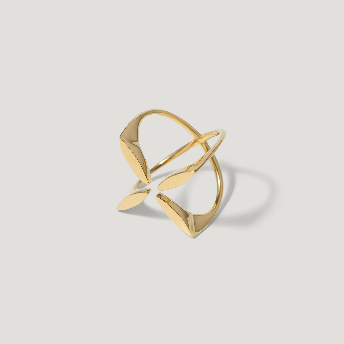Modern open gold ring with abstract geometric shapes on a light background