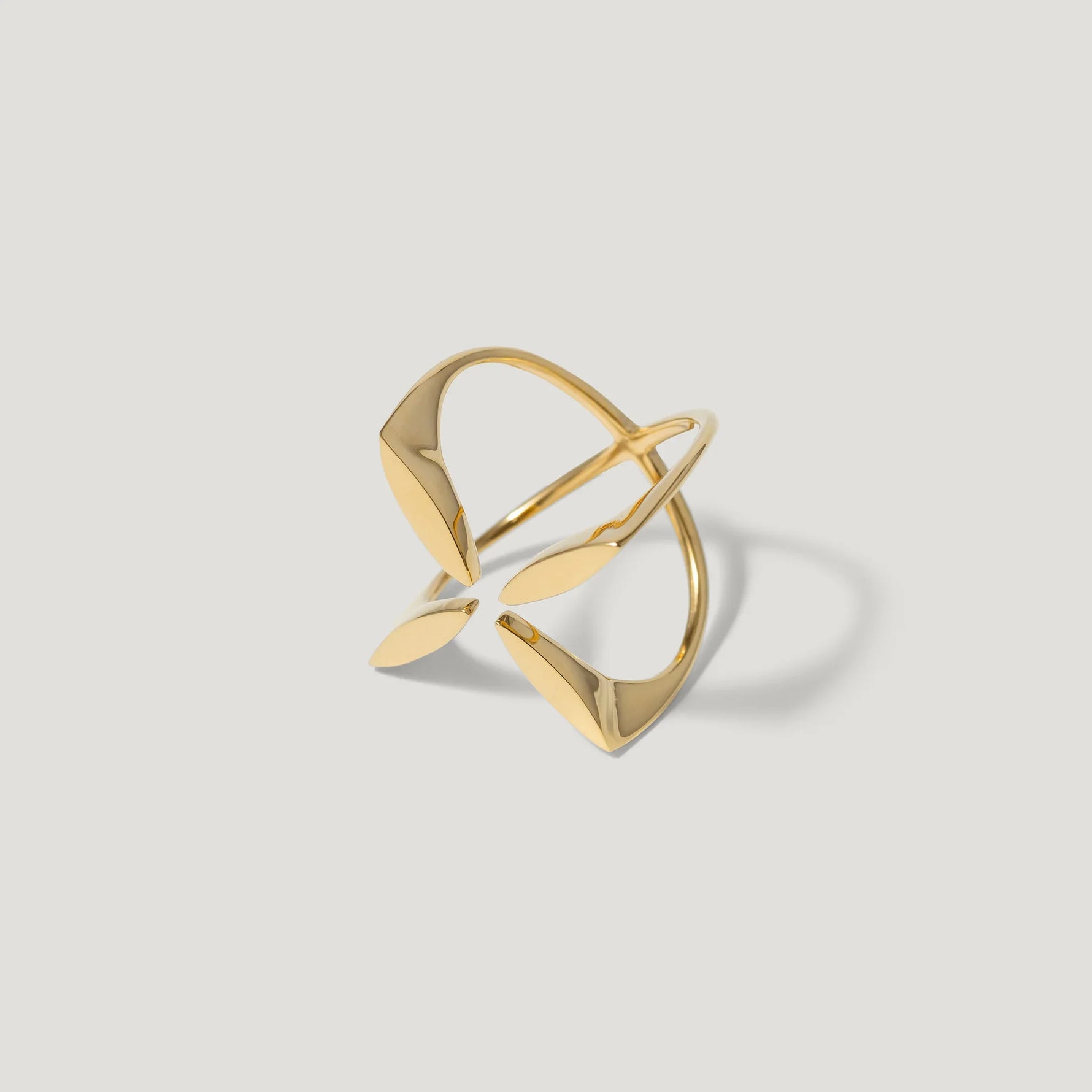 Modern open gold ring with abstract geometric shapes on a light background