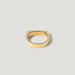 Minimalist gold ring with a flat square edge on a plain light background