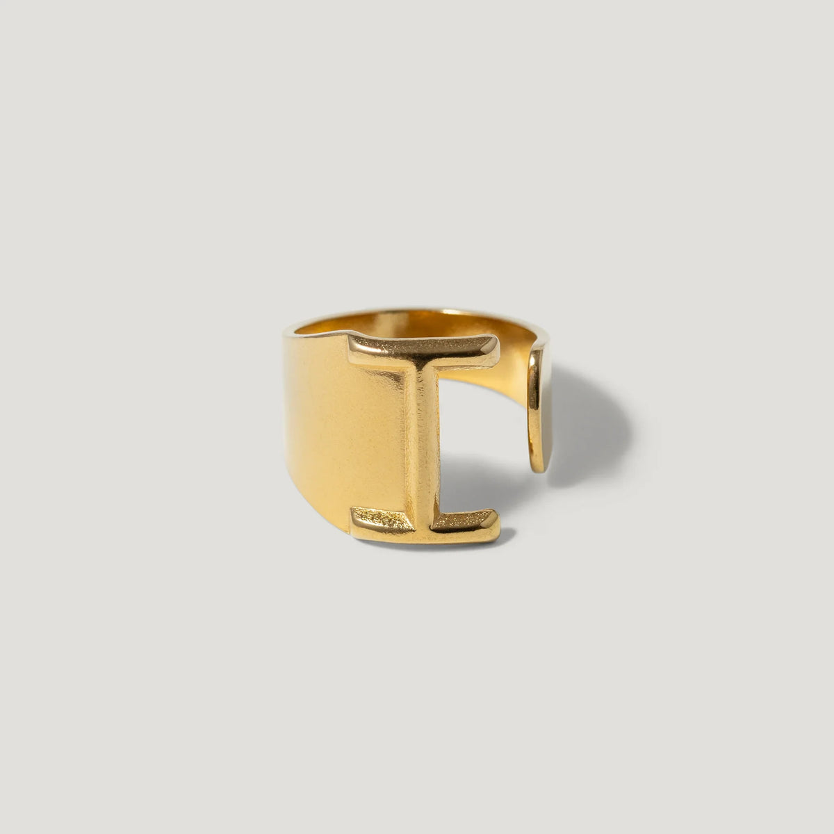 Gold open band ring with bold geometric design on light background