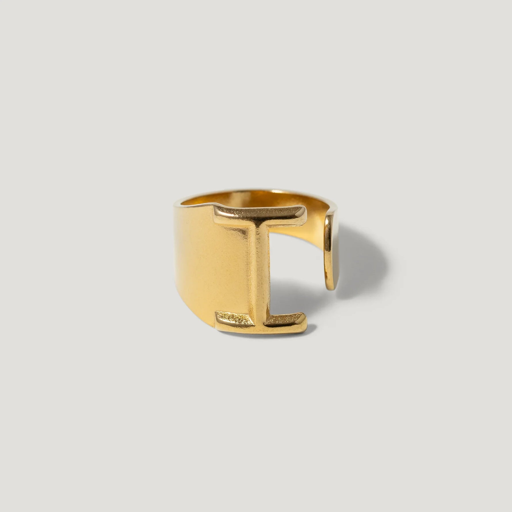 Gold open band ring with bold geometric design on light background