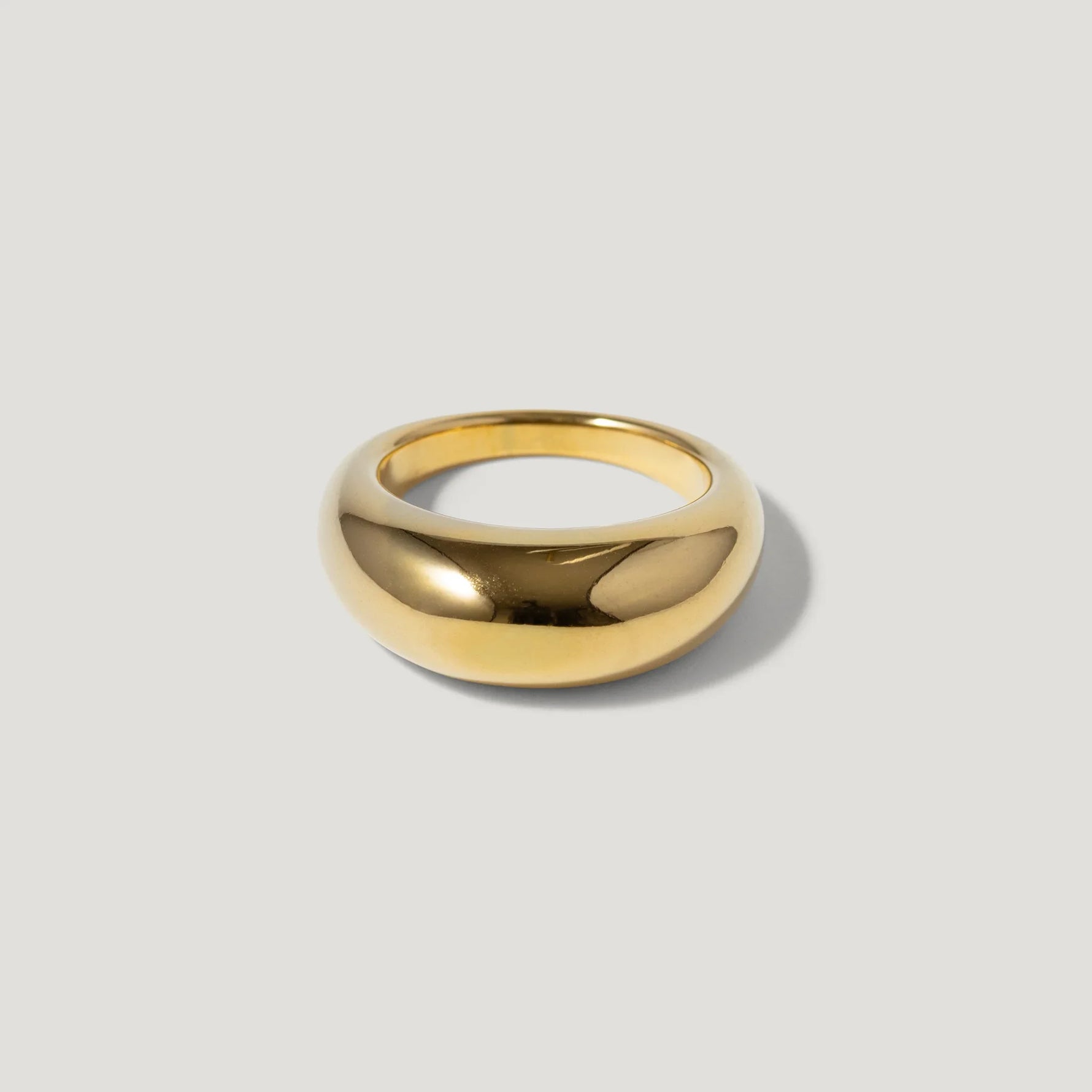 Minimalist gold dome ring with polished finish on a light background