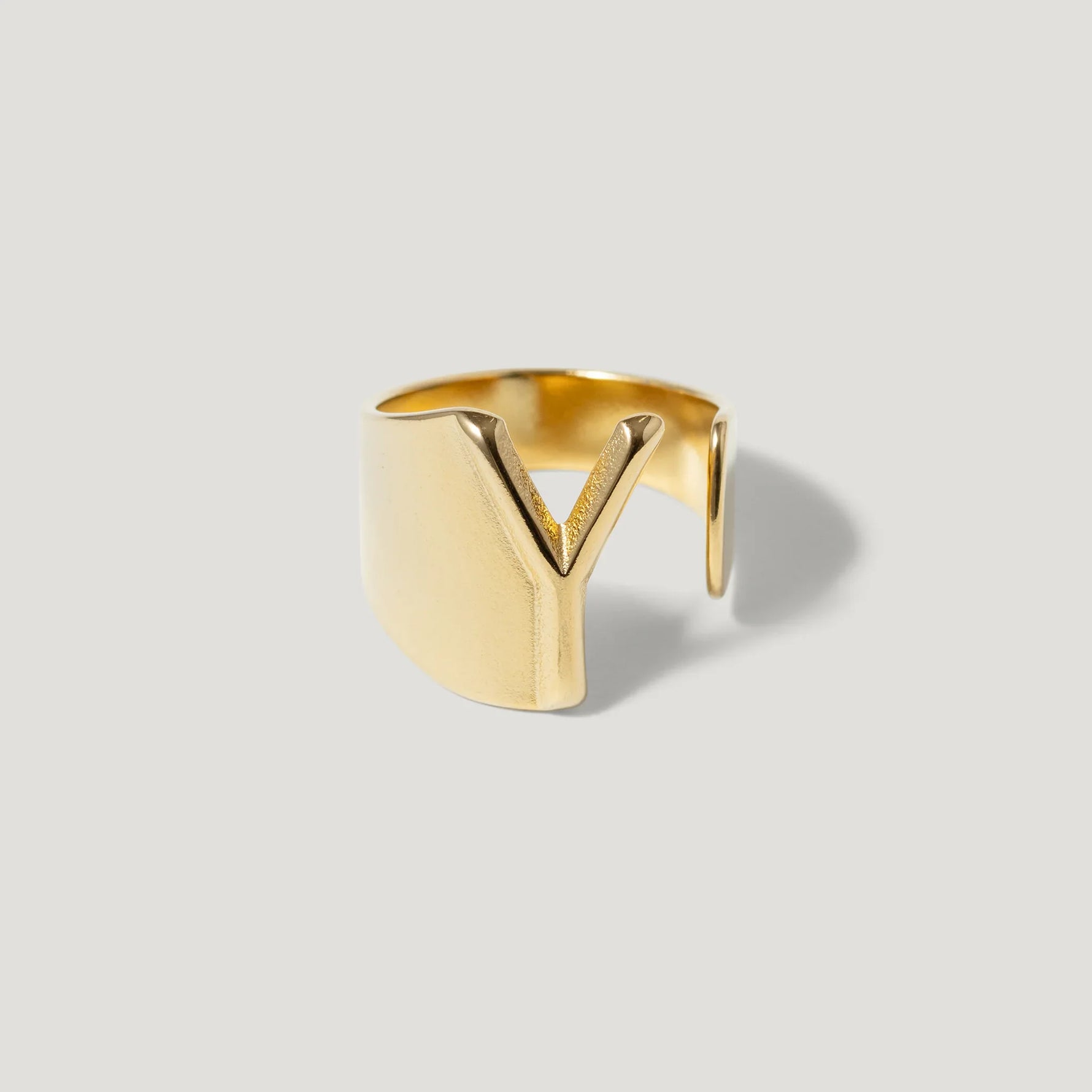 Modern gold ring with a sculptural V-shaped cutout on a light background