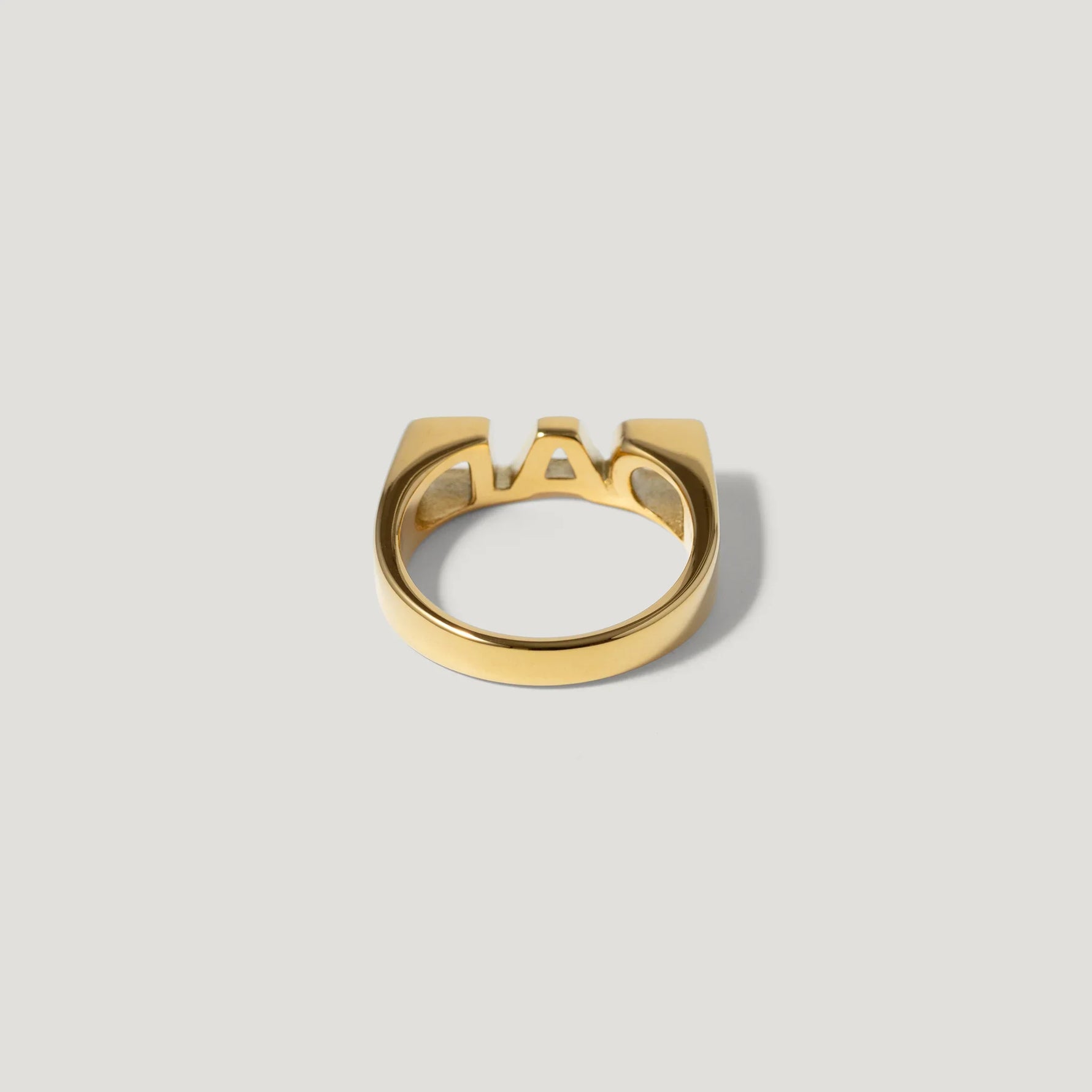 Modern gold ring with geometric cutout design on a light background
