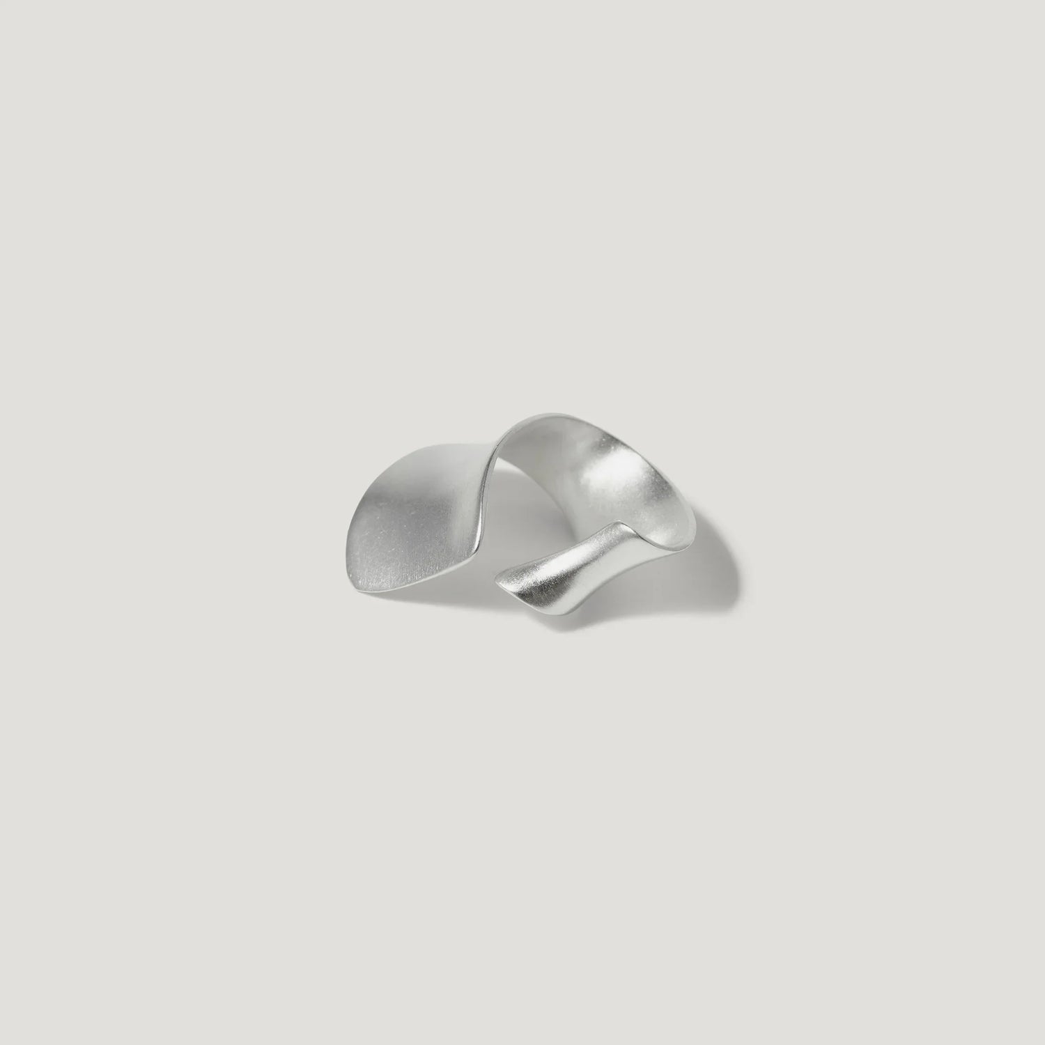 Modern sculptural silver ring with organic wave design on light background
