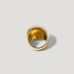 Chunky gold statement ring with smooth, polished finish on a plain light background