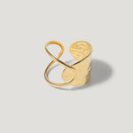Wide gold cuff ring with abstract, sculptural open design on a light background