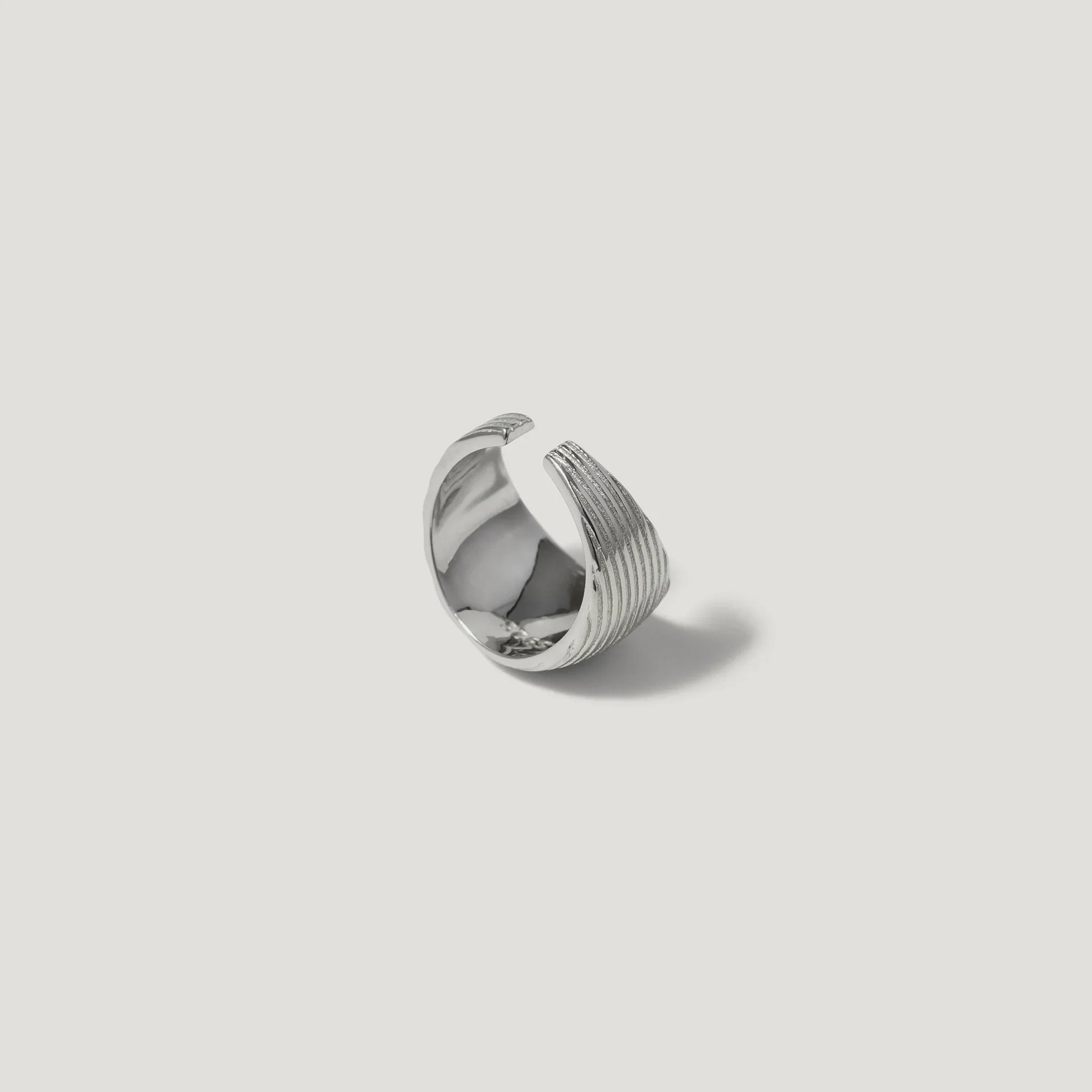 Sterling silver textured open ring with ribbed design on white background