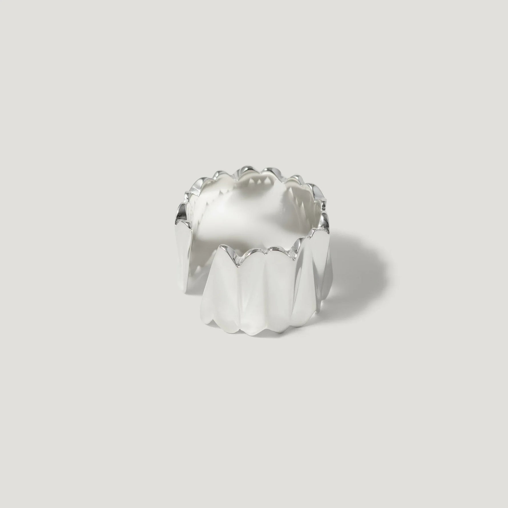 Modern silver ring with sculpted, wavy texture on plain light background