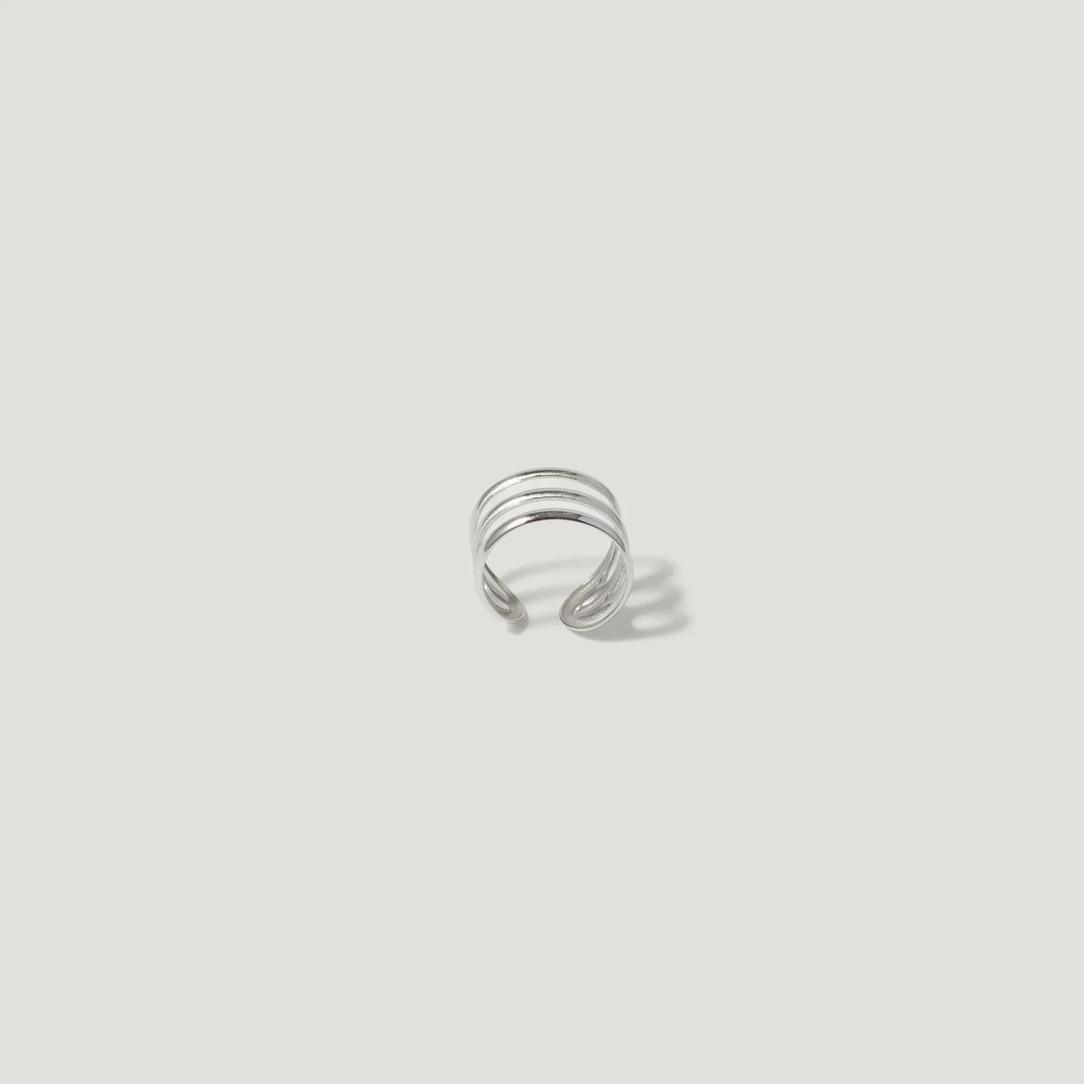 Minimalist silver ear cuff with layered bands on a white background