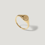 Gold signet ring with engraved tree branch design on white background