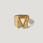Gold letter M signet ring with bold, modern design on neutral background
