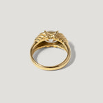 Gold solitaire ring with detailed band and prong-set gemstone on light background