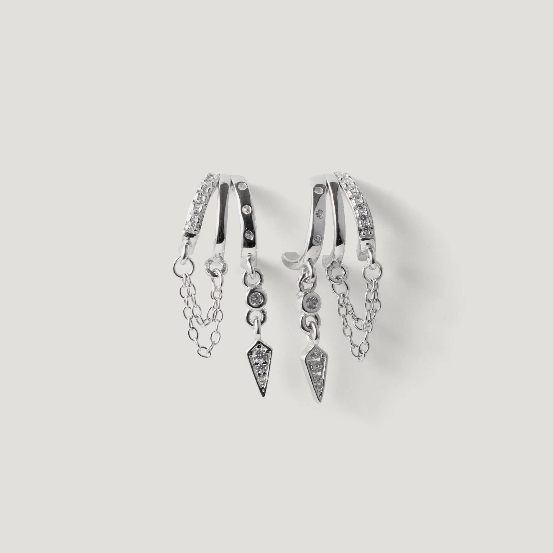 Silver hoop earrings with dangling chains and geometric diamond charms on white background