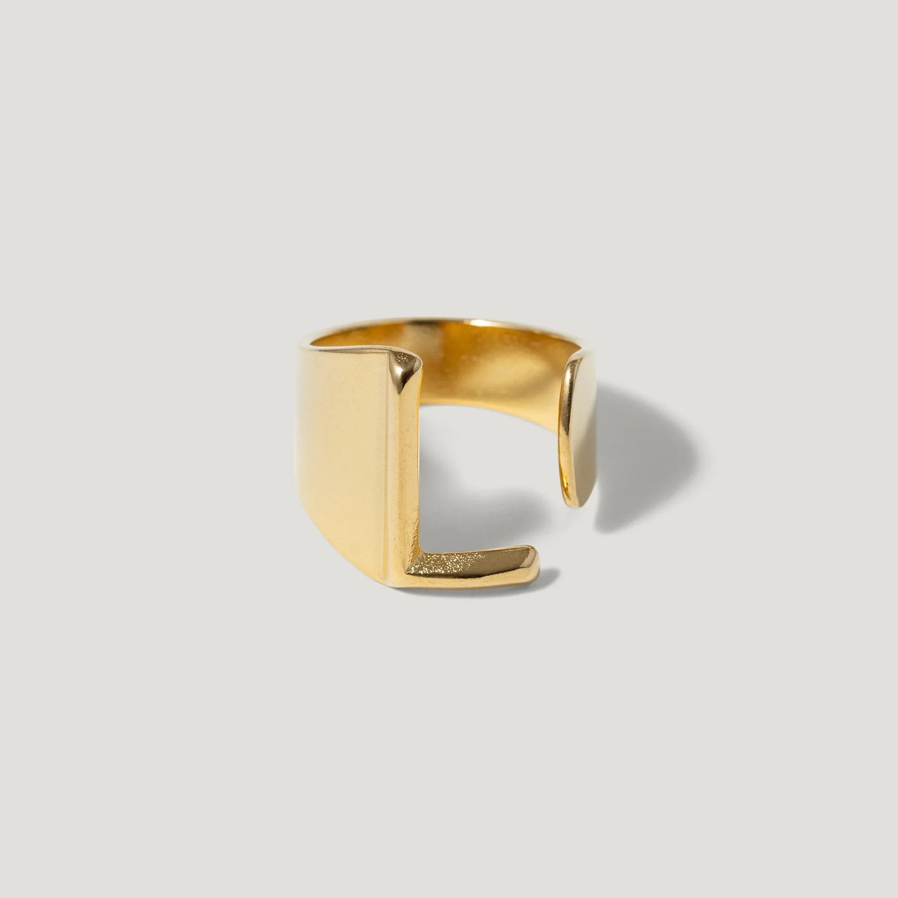 Minimalist open gold ring with geometric squared edges on a light background