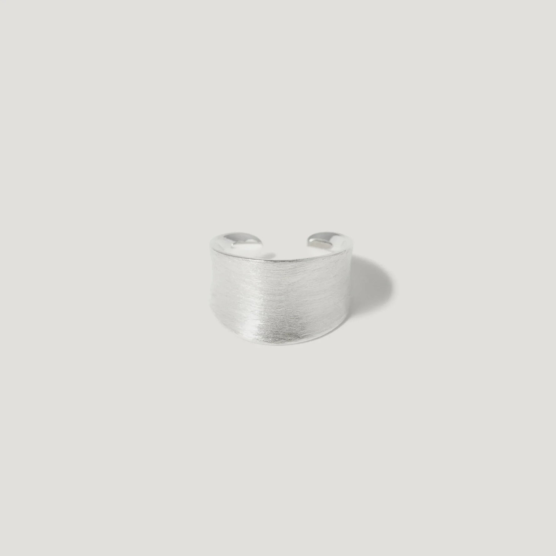 Wide brushed silver adjustable ring on white background, minimalist jewelry.