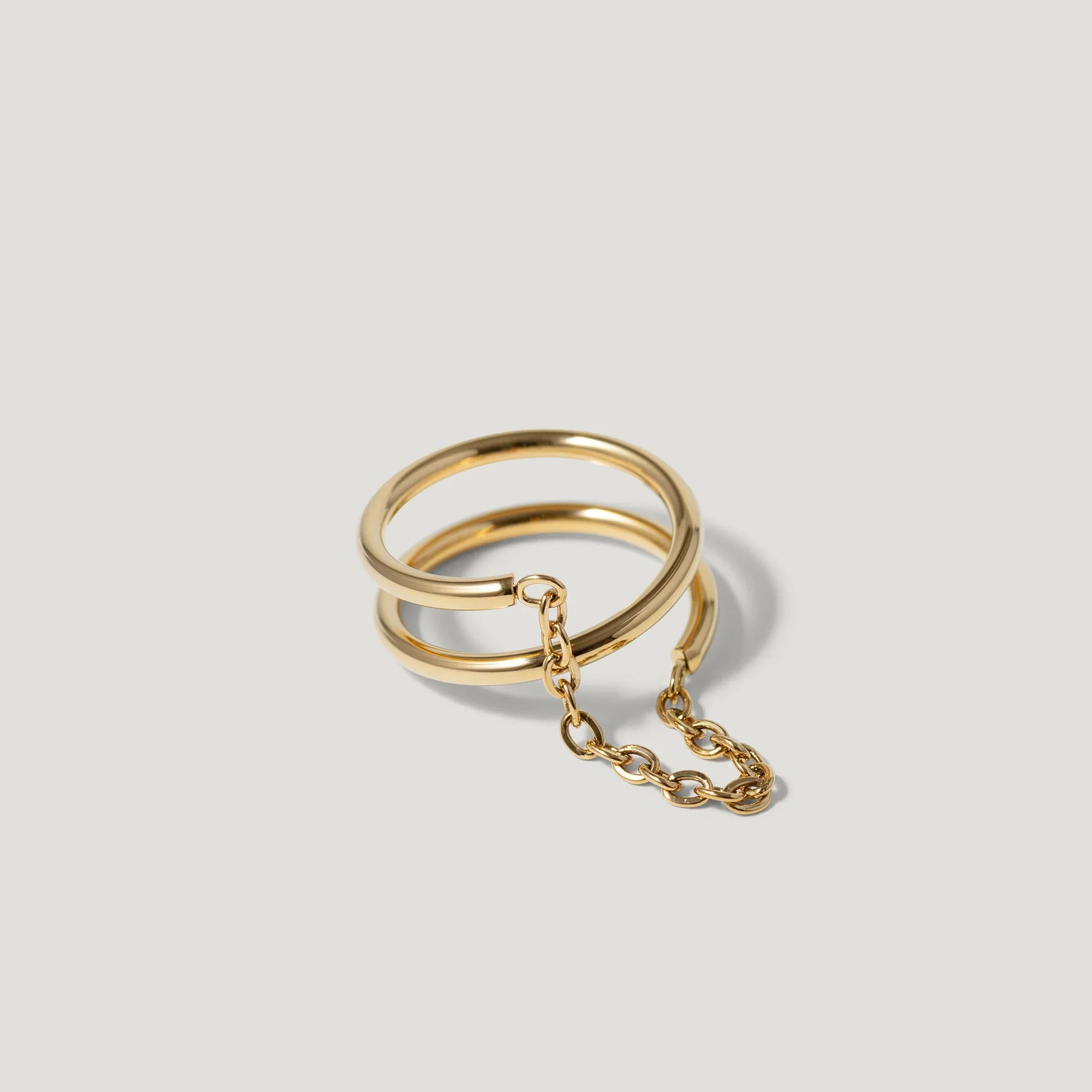 Gold double band chain ring on light background, minimalist jewelry design